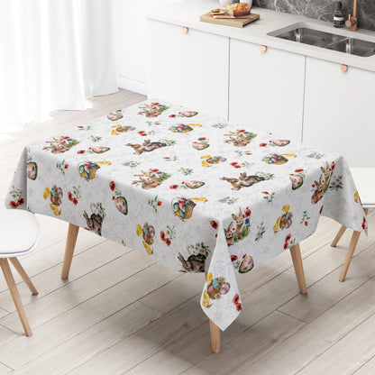 Wachstuch-Tischdecke mit Osterdessin auf weißem Hintergrund mit feinen silberfarbenen Ornamenten. Das Muster zeigt niedliche Hasen, flauschige Küken, bunte Ostereier in Körbchen sowie zarte Frühlingsblumen und Blütenzweige. Die liebevoll gestalteten Motive in harmonischen Pastelltönen verleihen der Tischdecke eine freundliche, frühlingshafte und festliche Ausstrahlung.
