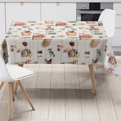 Wachstuch-Tischdecke mit niedlichen Katzenmotiven, Körben, Pflanzen und dekorativen Naturdetails in warmen Beige- und Orangetönen auf heller Holzoptik.
