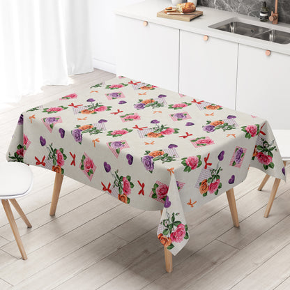 Rechteckige Wachstuch-Tischdecke mit romantischem Blumenmuster auf cremefarbenem Hintergrund. Rosa, lilafarbene und apricotfarbene Rosen wechseln sich mit grünen Blättern, karierten rosa Elementen, kleinen Schleifen und lilafarbenen Herzen mit „Love“-Aufschrift ab. Die Tischdecke fällt dekorativ über die Tischkanten und vermittelt einen verspielten, floralen Landhausstil.