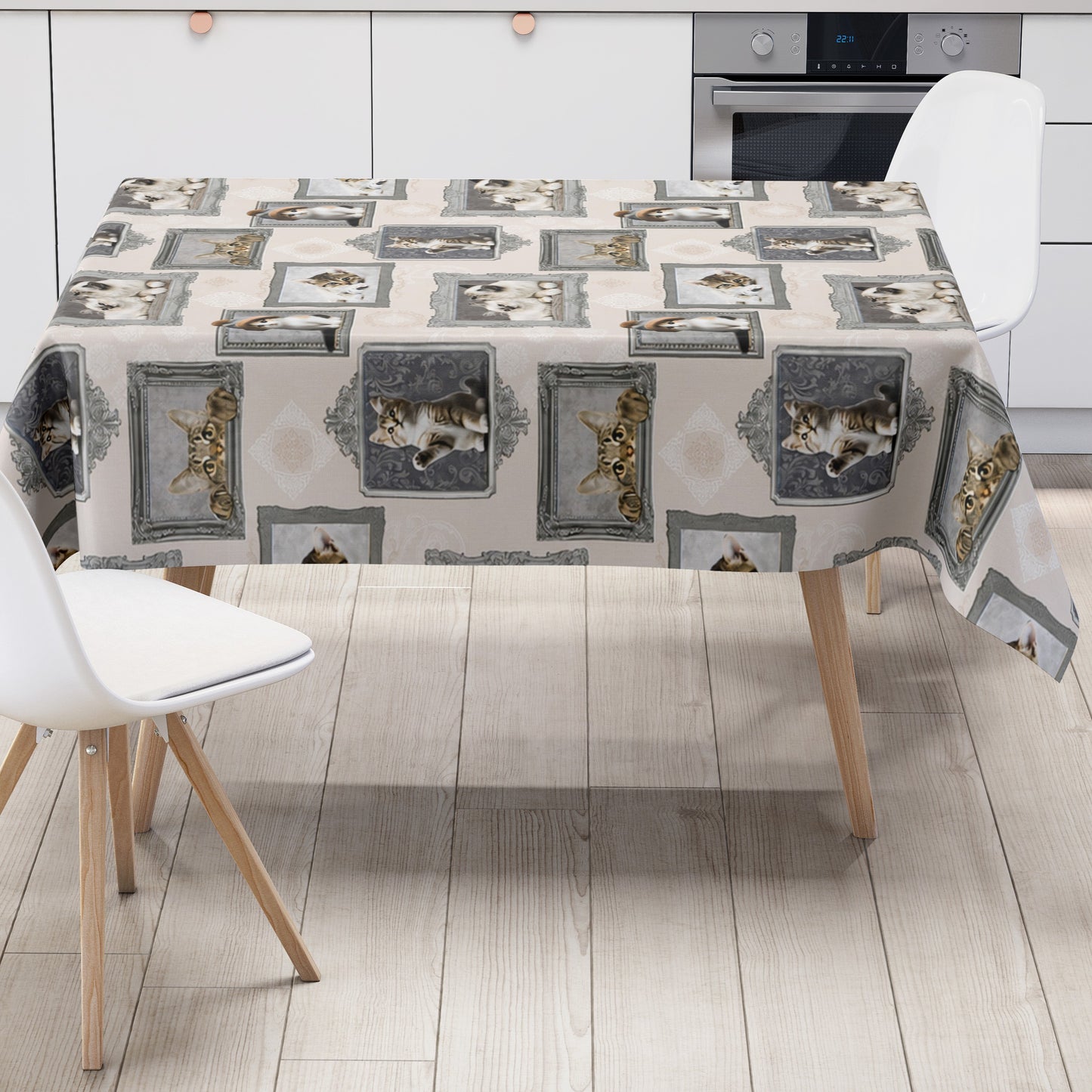 Wachstuch-Tischdecke mit cremefarbenem Hintergrund und dekorativem Katzenmotiv im Vintage-Stil. Verschiedene Katzenporträts in grauen und silbernen Bilderrahmen sind gleichmäßig über die Tischdecke verteilt. Das Design zeigt flauschige Kätzchen und neugierige Katzen mit dezenten Ornamentmustern zwischen den Rahmen.