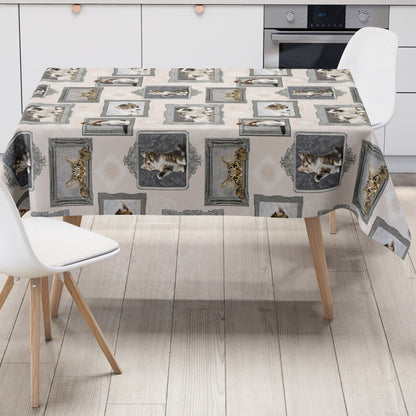 Wachstuch-Tischdecke mit cremefarbenem Hintergrund und dekorativem Katzenmotiv im Vintage-Stil. Verschiedene Katzenporträts in grauen und silbernen Bilderrahmen sind gleichmäßig über die Tischdecke verteilt. Das Design zeigt flauschige Kätzchen und neugierige Katzen mit dezenten Ornamentmustern zwischen den Rahmen.