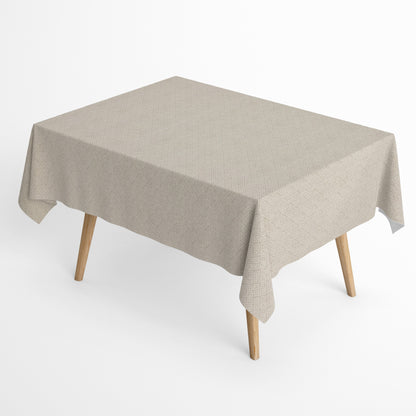 Jacquard-Tischdecke aus beschichteter Baumwolle mit Fleckenschutz, beige mit filigranem Rauten- und Blumenmuster, auf einem Holztisch drapiert.