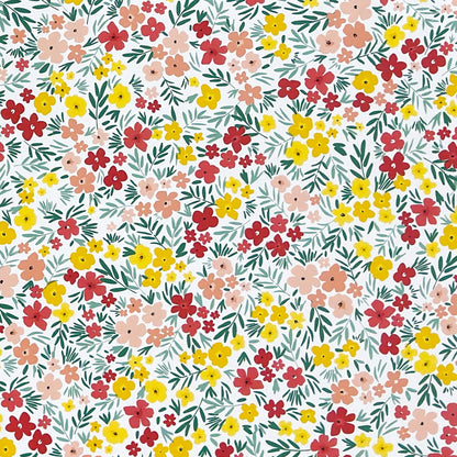 Bunte Wachstuch-Tischdecke mit dichtem Streublumenmuster in Rot, Gelb und Rosa sowie grünen Blättern auf hellem Hintergrund, über eine rechteckige Tischkante drapiert.