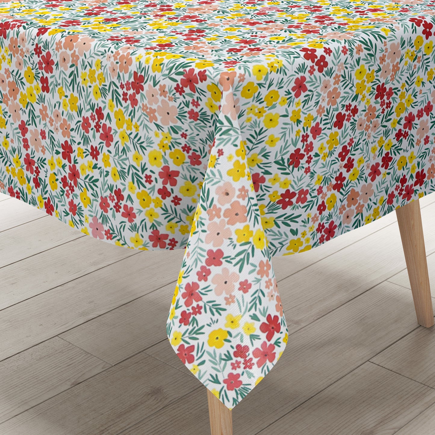 Bunte Wachstuch-Tischdecke mit dichtem Streublumenmuster in Rot, Gelb und Rosa sowie grünen Blättern auf hellem Hintergrund, über eine rechteckige Tischkante drapiert.