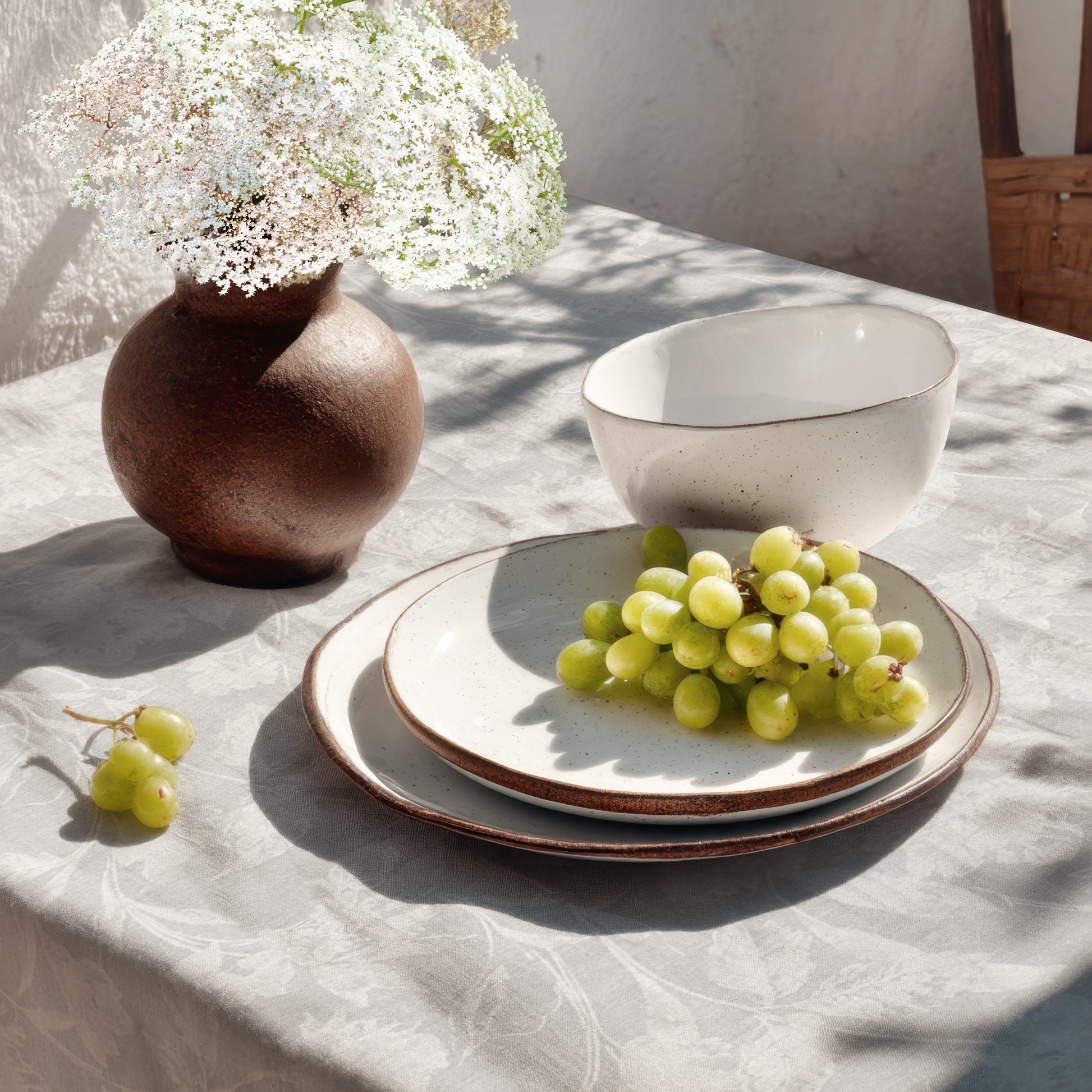 Beschichtete Baumwoll-Tischdecke mit Fleckenschutz im Design CARDUCHO, hellgrauer Hintergrund mit einem dezenten Ton-in-Ton-Allover-Muster aus filigranen Wiesenblumen, Gräsern und Blättern in Weiß.