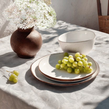 Beschichtete Baumwoll-Tischdecke mit Fleckenschutz im Design CARDUCHO, hellgrauer Hintergrund mit einem dezenten Ton-in-Ton-Allover-Muster aus filigranen Wiesenblumen, Gräsern und Blättern in Weiß.