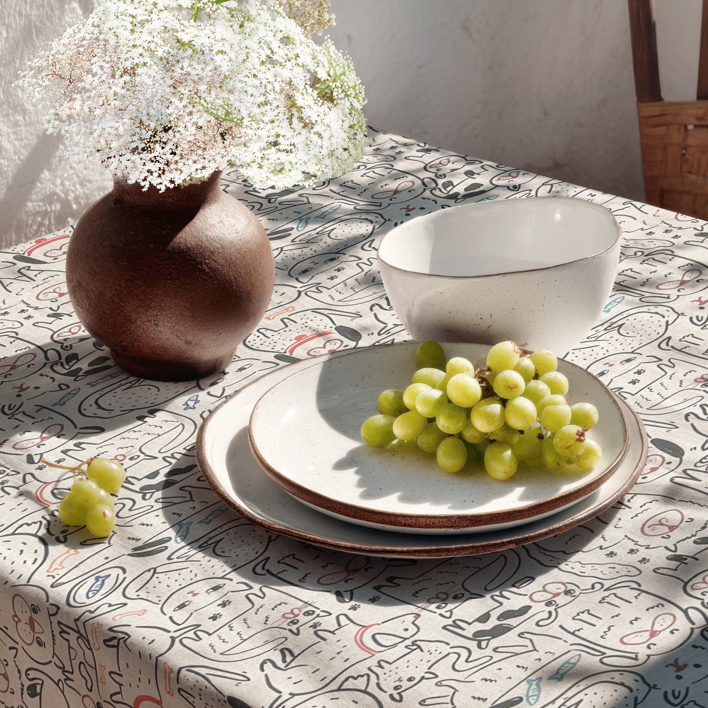 Beschichtete Baumwoll-Tischdecke mit Fleckenschutz im Design DP160, bedruckt mit einem verspielten Allover-Muster aus gezeichneten Hunden und Katzen sowie kleinen Motiven wie Knochen, Fischen, Pfoten und Halsbändern auf hellem Hintergrund.