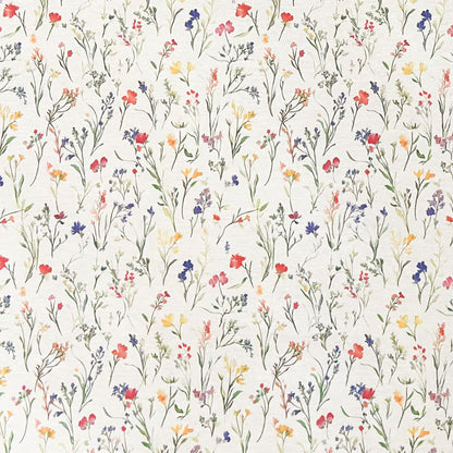 Beschichtete Baumwoll-Tischdecke mit zartem Streublumenmuster auf hellem Hintergrund. Filigrane Wildblumen und Gräser in Rot, Blau, Gelb und Rosa verteilen sich gleichmäßig über die Oberfläche. Über eine Tischecke drapiert, mit sichtbaren hellen Holzbeinen.