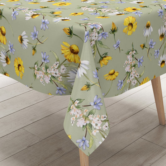 Wachstuch-Tischdecke mit Wiesenblumenmuster auf salbeigrünem Hintergrund. Gelbe Blüten, weiße Margeriten, kleine blaue Blumen und zarte weiße Blütenzweige sind gleichmäßig verteilt und sorgen für eine frische, natürliche Ausstrahlung.