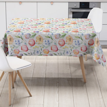 Wachstuch-Tischdecke mit zartem Aquarell-Blumenmuster auf hellem Hintergrund. Tulpen, Mohnblumen und kleine Blüten in Rosa, Orange, Gelb, Blau und Violett werden von grünen Blättern und feinen Zweigen ergänzt.