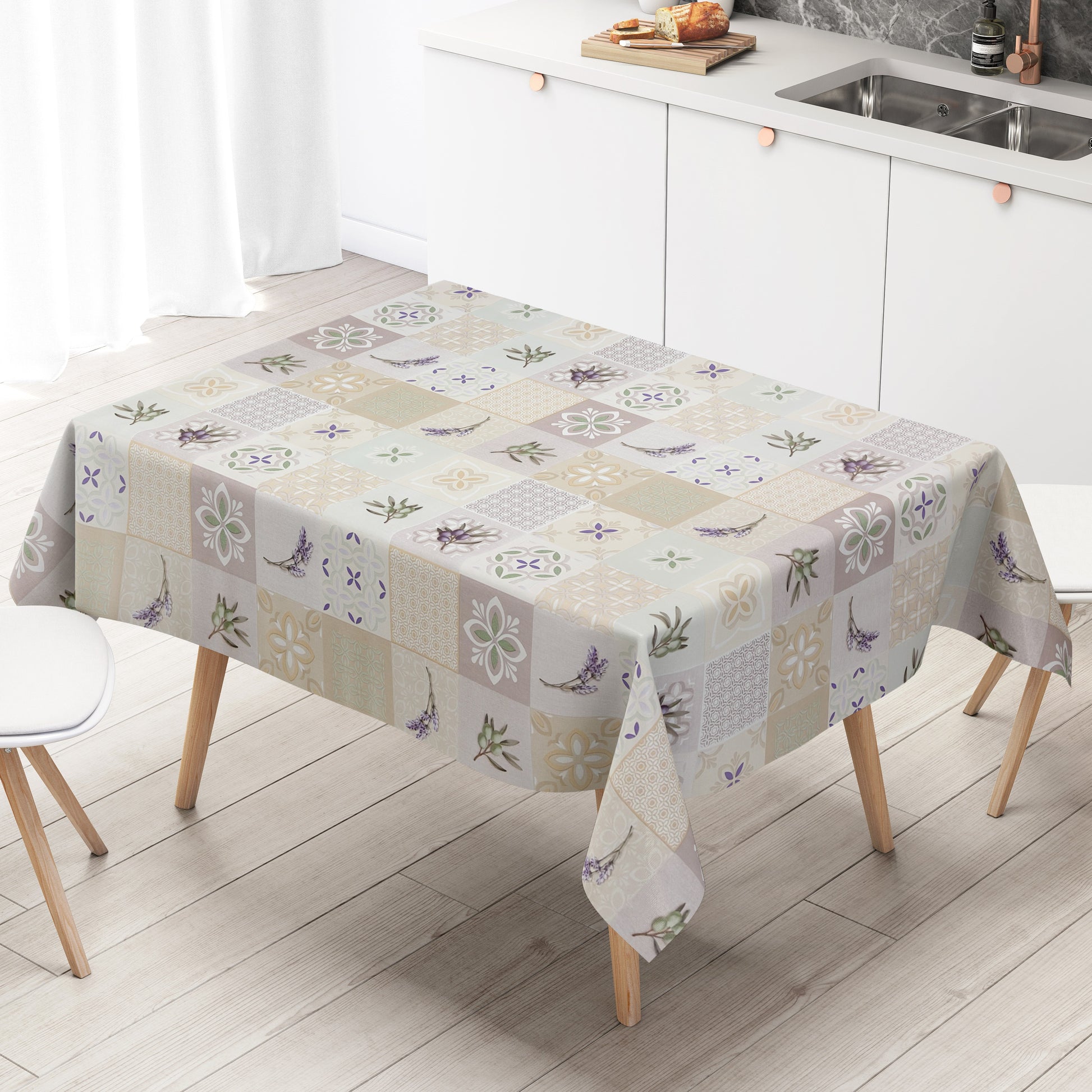 Wachstuch-Tischdecke mit Patchwork-Muster in Creme, Beige und Grau. Dekorative Fliesenornamente, stilisierte Blüten, Lavendel- und Olivenzweige in sanften Grün- und Lilatönen verleihen dem Design einen mediterranen Landhaus-Charme.