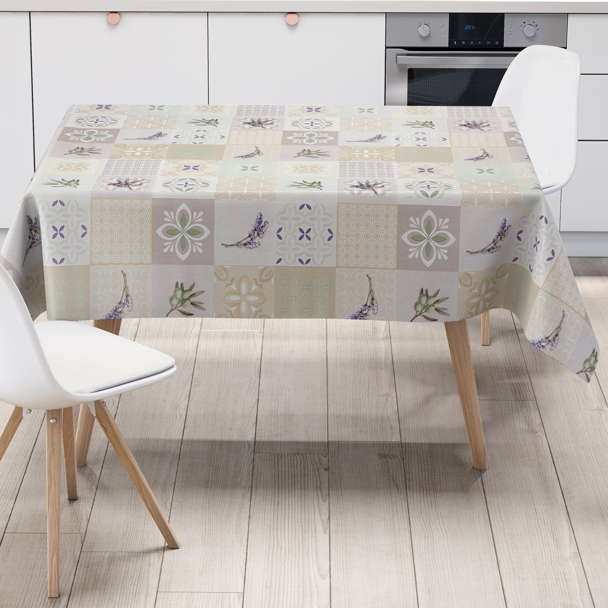 Wachstuch-Tischdecke mit Patchwork-Muster in Creme, Beige und Grau. Dekorative Fliesenornamente, stilisierte Blüten, Lavendel- und Olivenzweige in sanften Grün- und Lilatönen verleihen dem Design einen mediterranen Landhaus-Charme.