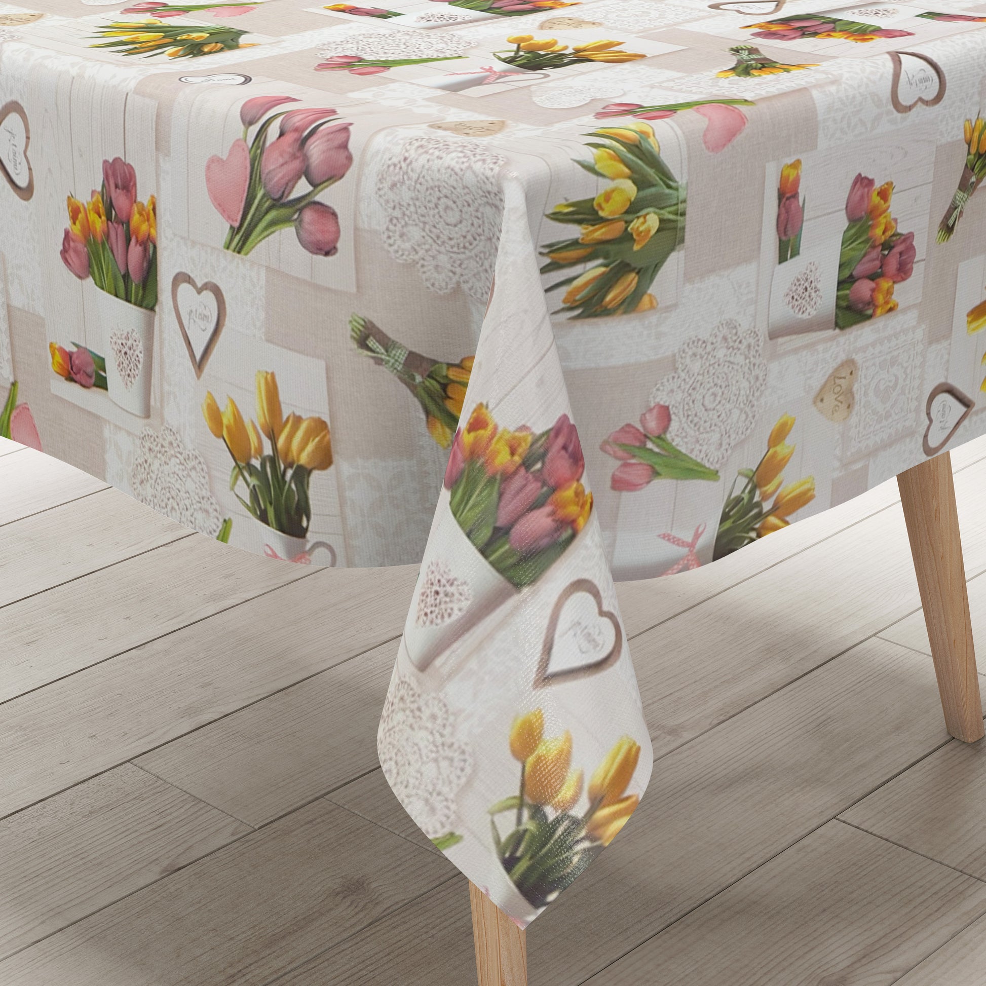 Rechteckige Wachstuch-Tischdecke in Beige und Creme mit romantischem Patchwork-Dessin. Das Muster zeigt rosa und gelbe Tulpensträuße, Herzen, Spitzenornamente und dekorative Landhaus-Elemente auf hellen Holzoptik-Hintergründen. Die frühlingshafte Farbgestaltung verleiht der Tischdecke einen gemütlichen Vintage-Charakter.