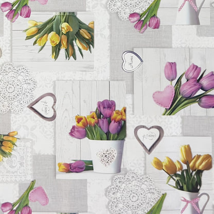 Wachstuch-Tischdecke mit romantischem Patchwork-Dessin in Hellgrau, Weiß und Creme. Das Muster zeigt rosa, violette und gelbe Tulpensträuße, Herzmotive, Spitzenornamente und Holzoptik-Elemente in harmonischer Anordnung. Die floralen Motive verleihen der Tischdecke einen frühlingshaften Landhausstil und schaffen eine freundliche, gemütliche Atmosphäre.