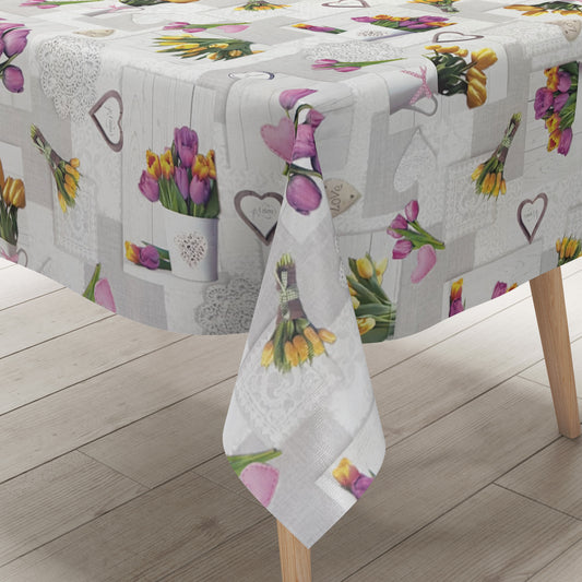 Wachstuch-Tischdecke mit romantischem Patchwork-Dessin in Hellgrau, Weiß und Creme. Das Muster zeigt rosa, violette und gelbe Tulpensträuße, Herzmotive, Spitzenornamente und Holzoptik-Elemente in harmonischer Anordnung. Die floralen Motive verleihen der Tischdecke einen frühlingshaften Landhausstil und schaffen eine freundliche, gemütliche Atmosphäre.