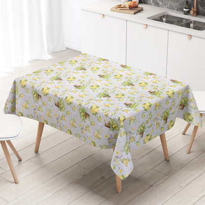 Wachstuch-Tischdecke mit mediterranem Zitronenmuster in Aquarelloptik. Gelbe Zitronen, grüne Blätter, Zitronenbäumchen in Terrakottatöpfen sowie rustikale Holzelemente und Gläser mit Zitronengetränken auf hellem Hintergrund