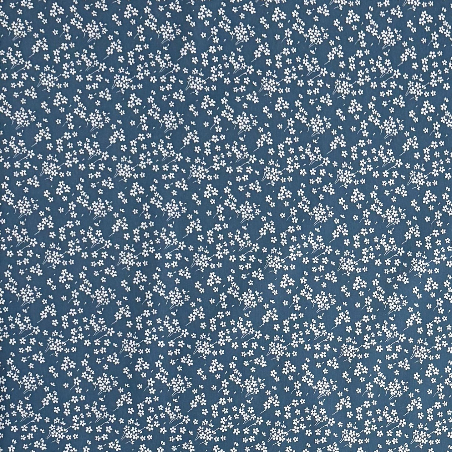 Die Jacquard Tischdecke aus beschichteter Baumwolle zeigt ein dezentes Streublumenmuster mit vielen kleinen, feinen Blüten in Weiß auf dunklem Hintergrund. Die gleichmäßige Verteilung wirkt ruhig und elegant.