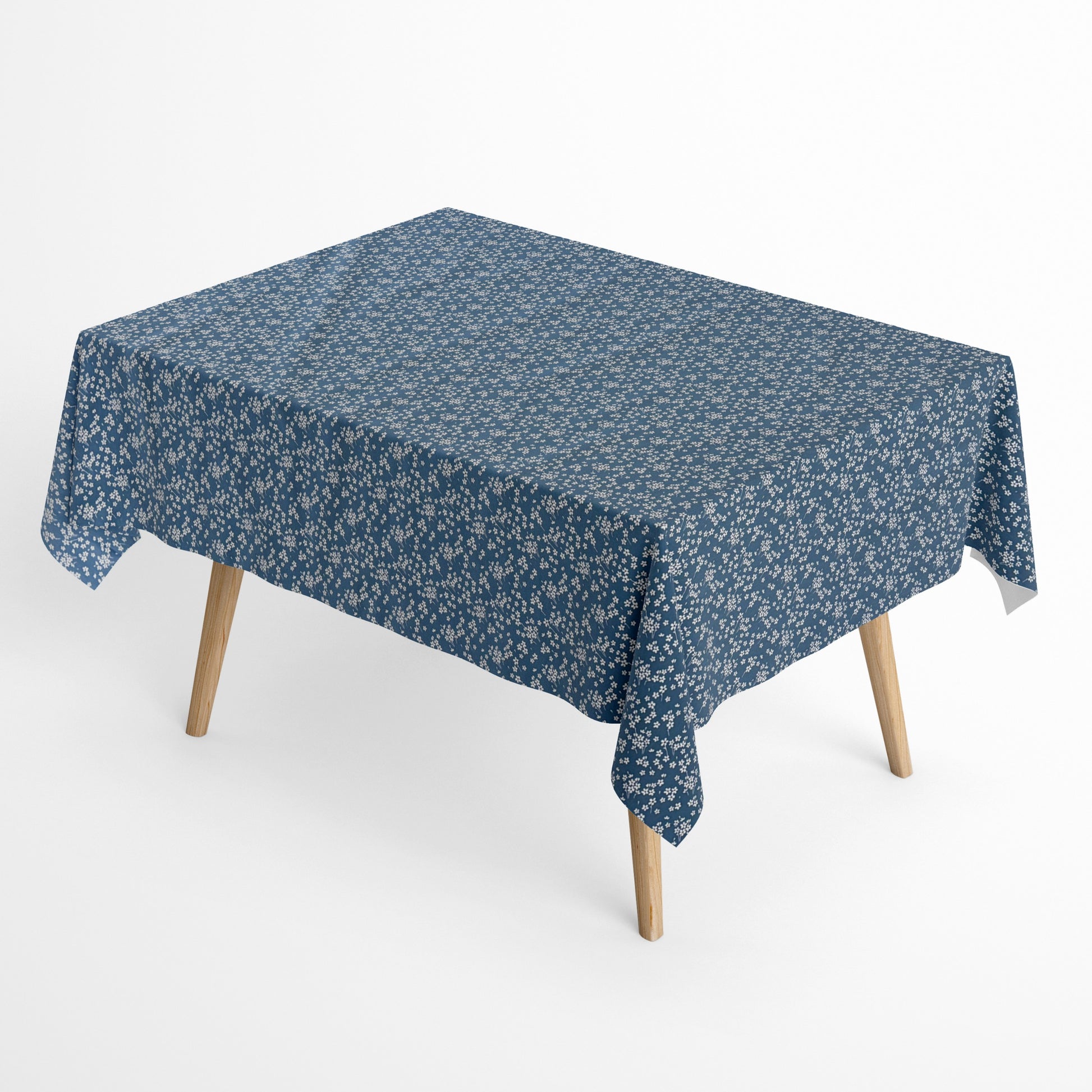 Die Jacquard Tischdecke aus beschichteter Baumwolle zeigt ein dezentes Streublumenmuster mit vielen kleinen, feinen Blüten in Weiß auf dunklem Hintergrund. Die gleichmäßige Verteilung wirkt ruhig und elegant.