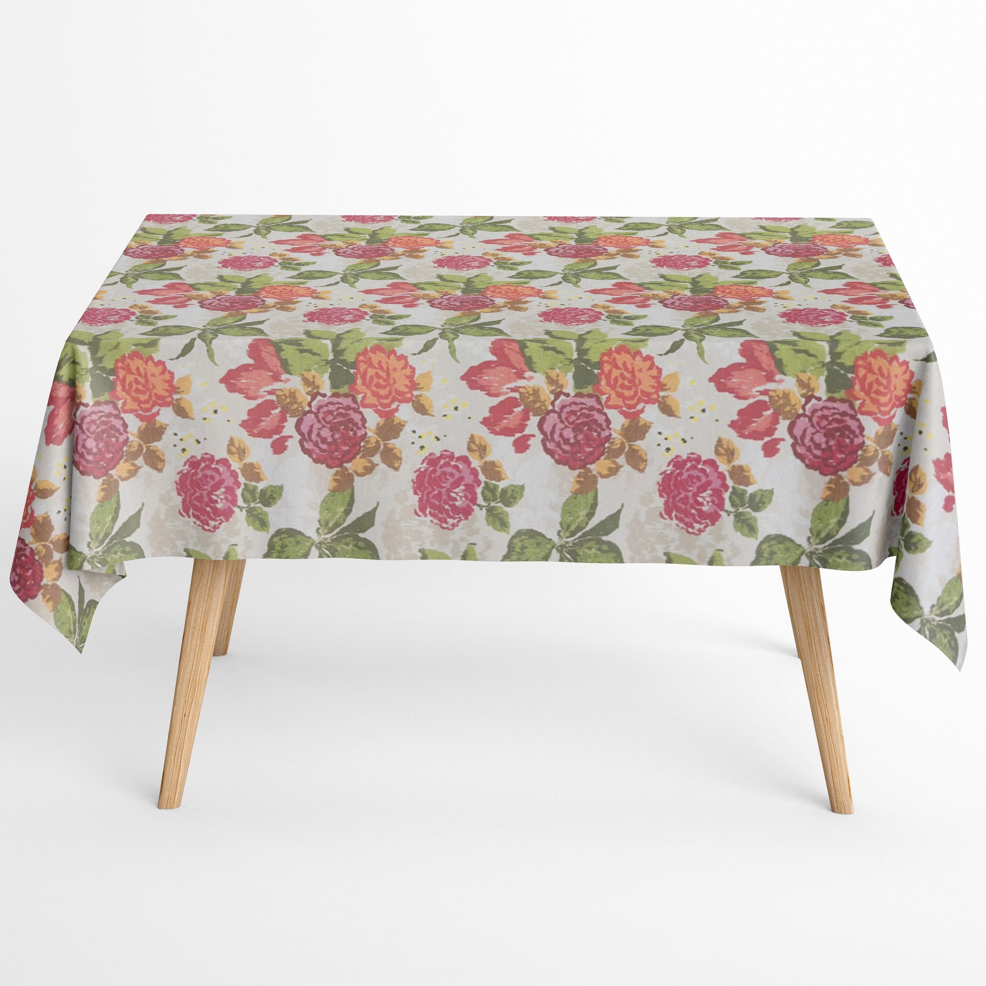 Beschichtete Baumwoll-Tischdecke mit großem floralem Muster auf hellem Hintergrund. Auffällige Blüten in Pink, Rot und Orange sowie grüne Blätter verteilen sich über die Oberfläche. Über eine Tischecke drapiert, mit sichtbaren hellen Holzbeinen.